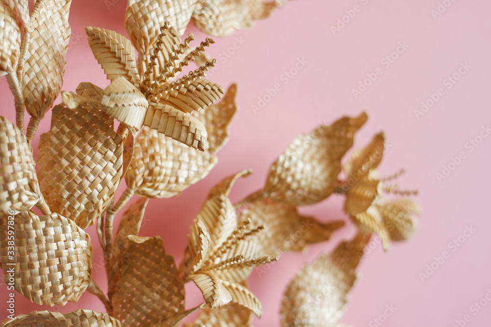 Branch with leaves and flowers is made of straw. Decoration of straw on a pink background. Decor. Fragment closeup. Shallow depth of field (DOF) Branch with leaves and flowers is made of straw. Decoration of straw on a pink background. Decor. Fragment closeup. Shallow depth of field (DOF)