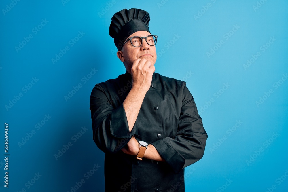 Middle age handsome grey-haired chef man wearing cooker uniform and hat with hand on chin thinking about question, pensive expression. Smiling and thoughtful face. Doubt concept. Middle age handsome grey-haired chef man wearing cooker uniform and hat with hand on chin thinking about question, pensive expression. Smiling and thoughtful face. Doubt concept.
