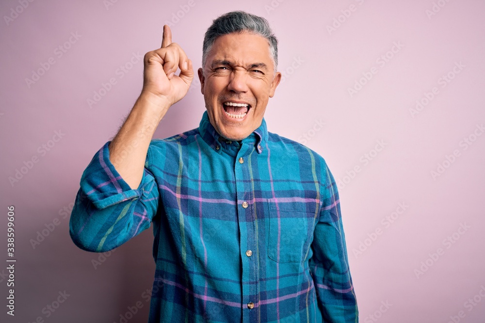 Middle age handsome grey-haired man wearing casual shirt over isolated pink background pointing finger up with successful idea. Exited and happy. Number one. Middle age handsome grey-haired man wearing casual shirt over isolated pink background pointing finger up with successful idea. Exited and happy. Number one.