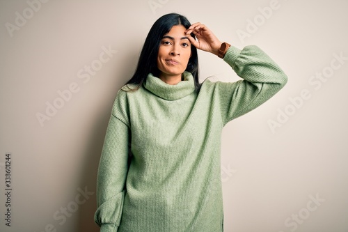 Young beautiful hispanic woman wearing green winter sweater over isolated background worried and stressed about a problem with hand on forehead, nervous and anxious for crisis © Krakenimages.com