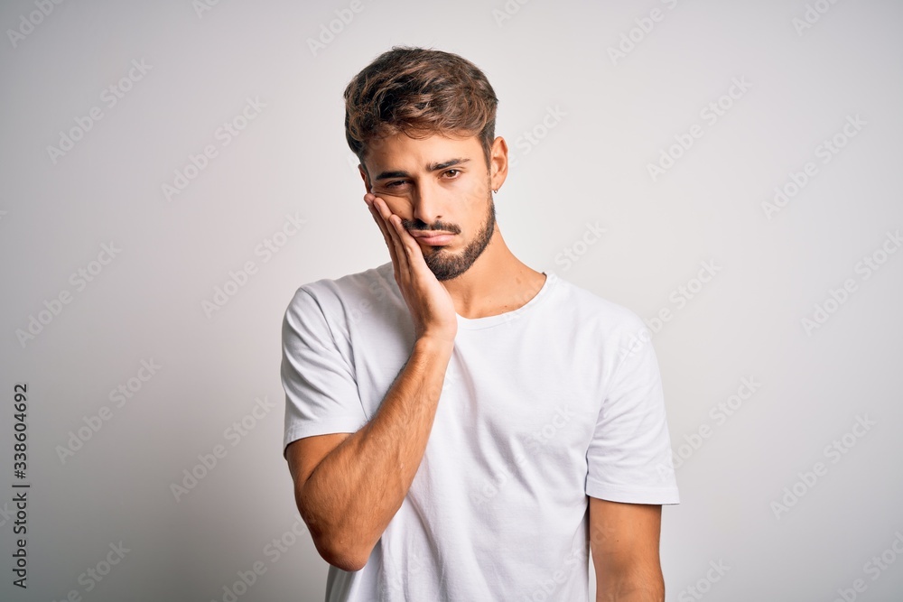Young handsome man with beard wearing casual t-shirt standing over white background thinking looking tired and bored with depression problems with crossed arms. Young handsome man with beard wearing casual t-shirt standing over white background thinking looking tired and bored with depression problems with crossed arms.