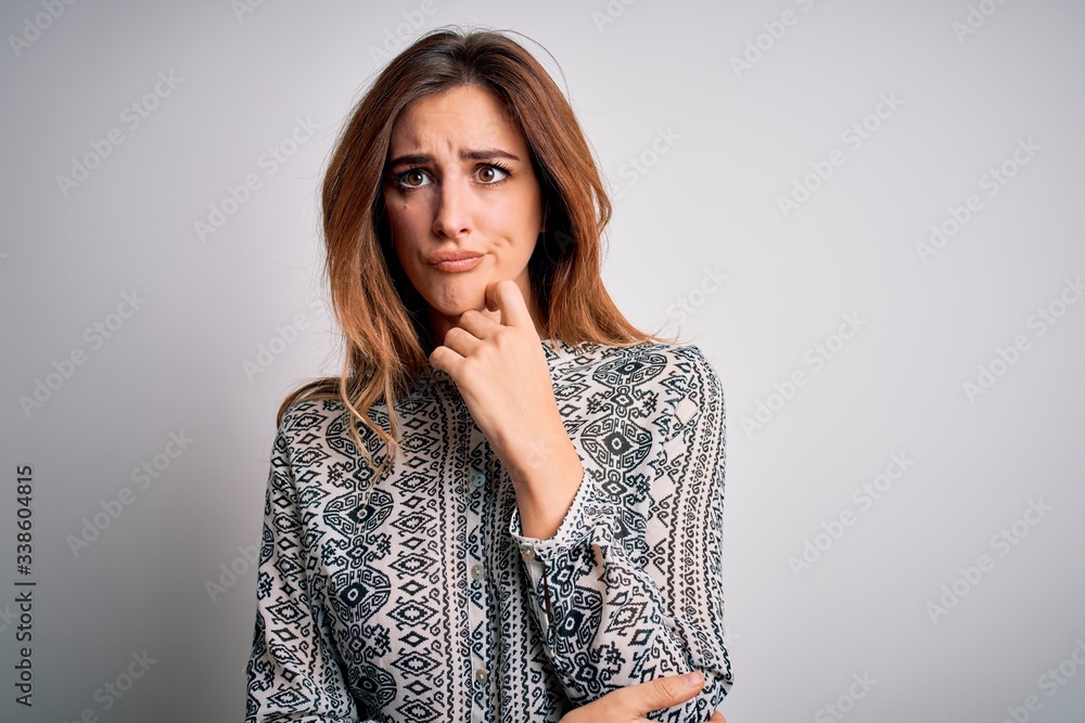 Young beautiful brunette woman wearing casual shirt standing over isolated white background with hand on chin thinking about question, pensive expression. Smiling with thoughtful face. Doubt concept. Young beautiful brunette woman wearing casual shirt standing over isolated white background with hand on chin thinking about question, pensive expression. Smiling with thoughtful face. Doubt concept.