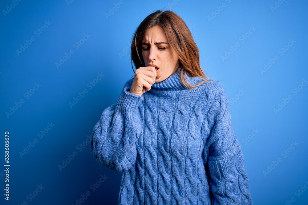 Young beautiful brunette woman wearing casual turtleneck sweater over blue background feeling unwell and coughing as symptom for cold or bronchitis. Health care concept. Young beautiful brunette woman wearing casual turtleneck sweater over blue background feeling unwell and coughing as symptom for cold or bronchitis. Health care concept.