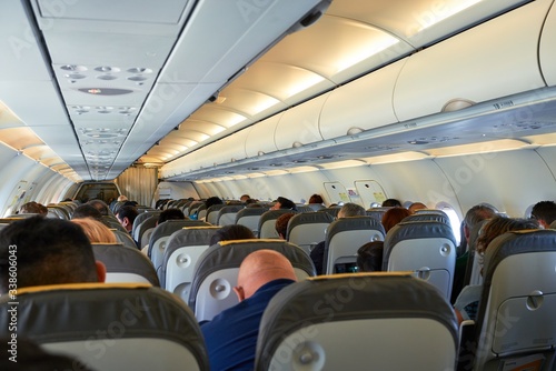 Passengers and crew sitting on airplane seats, view of the passengers and attendants inside cabin