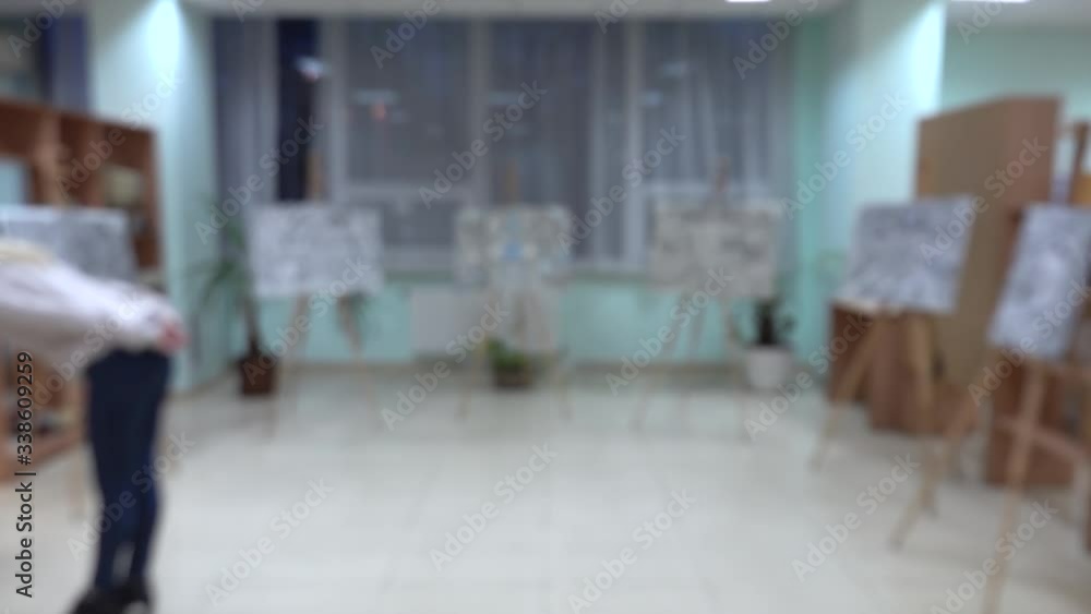 Blurred video of girl examines paintings of public library with bookshelfs Blurred video of girl examines paintings of public library with bookshelfs