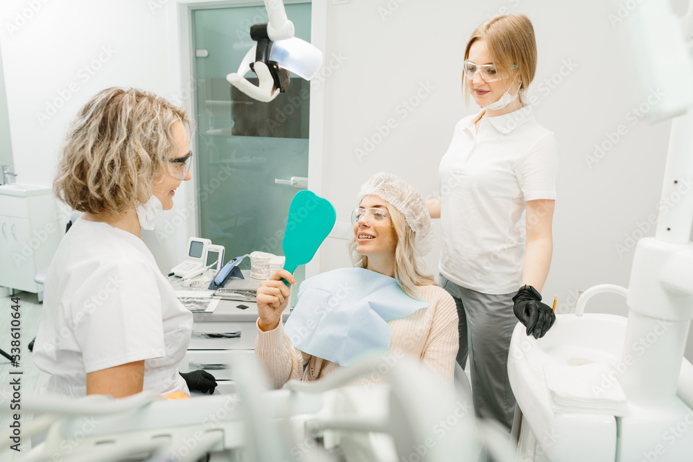 Female dentist in dental office talking with female patient and preparing for treatment Female dentist in dental office talking with female patient and preparing for treatment
