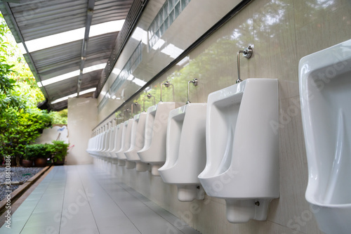 Close up row of outdoor white urinals men in public toilet.