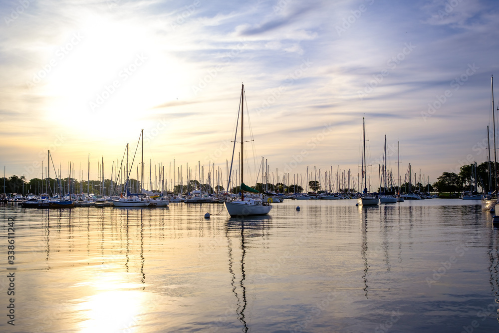 The sun rises over a quiet marina where sail boats are being stored.