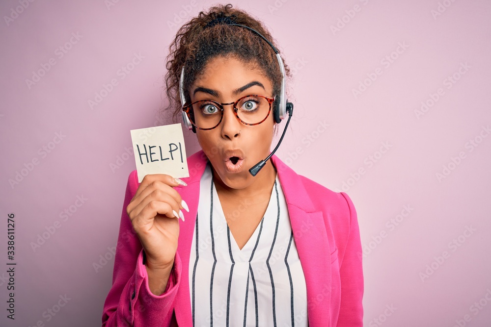 African american call center agent girl using headset holding reminder with help message scared in shock with a surprise face, afraid and excited with fear expression African american call center agent girl using headset holding reminder with help message scared in shock with a surprise face, afraid and excited with fear expression