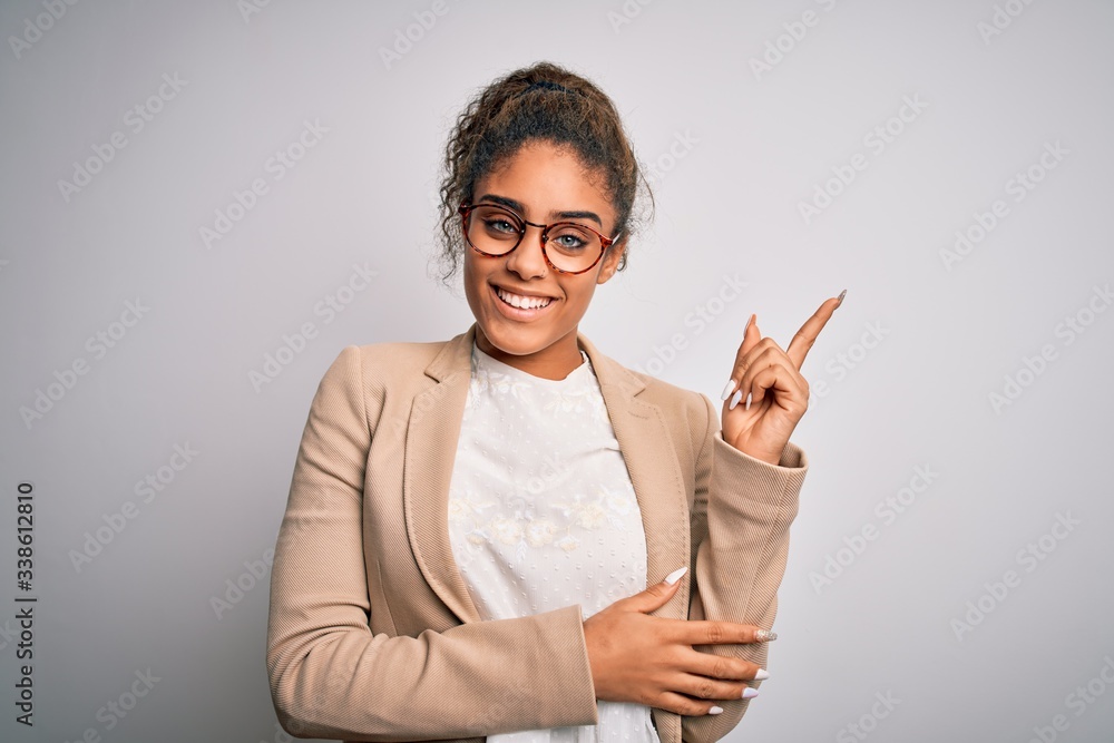 Beautiful african american businesswoman wearing jacket and glasses over white background with a big smile on face, pointing with hand and finger to the side looking at the camera. Beautiful african american businesswoman wearing jacket and glasses over white background with a big smile on face, pointing with hand and finger to the side looking at the camera.