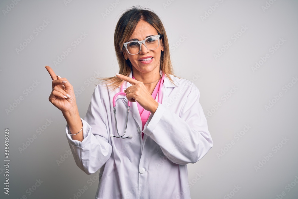 Middle age beautiful doctor woman wearing pink stethoscope over isolated white background smiling and looking at the camera pointing with two hands and fingers to the side. Middle age beautiful doctor woman wearing pink stethoscope over isolated white background smiling and looking at the camera pointing with two hands and fingers to the side.
