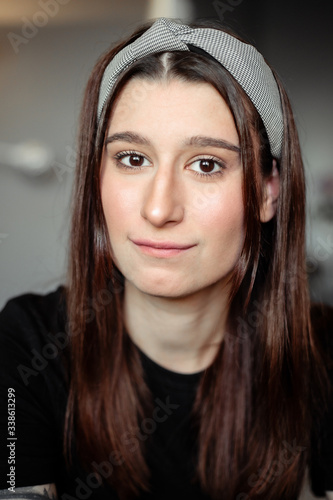 A young beautiful girl is in an apartment during self-isolation. She is dressed in black clothes and a bandana on her head