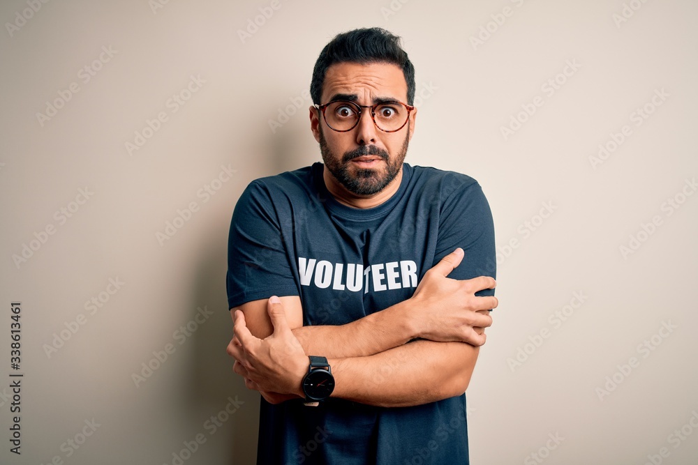 Handsome man with beard wearing t-shirt with volunteer message over white background shaking and freezing for winter cold with sad and shock expression on face Handsome man with beard wearing t-shirt with volunteer message over white background shaking and freezing for winter cold with sad and shock expression on face