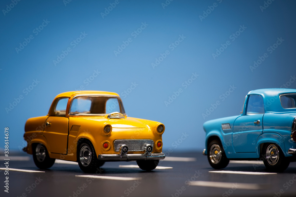 Two toy cas on a blue background and asphalt road. Two toy cas on a blue background and asphalt road.