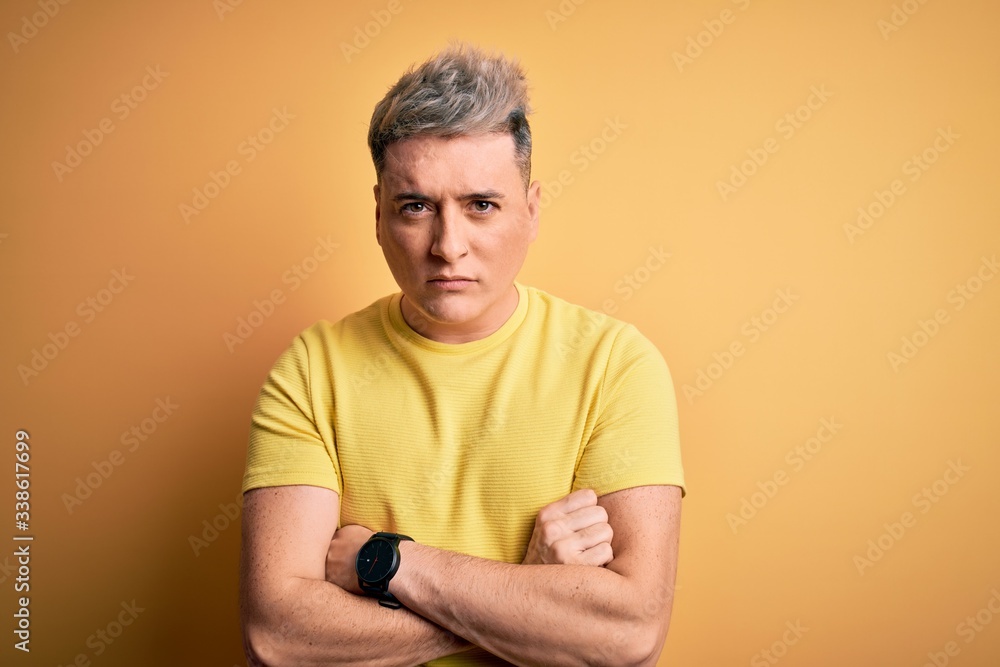 Young handsome modern man wearing yellow shirt over yellow isolated background skeptic and nervous, disapproving expression on face with crossed arms. Negative person. Young handsome modern man wearing yellow shirt over yellow isolated background skeptic and nervous, disapproving expression on face with crossed arms. Negative person.