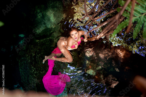 Beautiful teenage girl in a cenote from the Mayan Riviera in cloth.