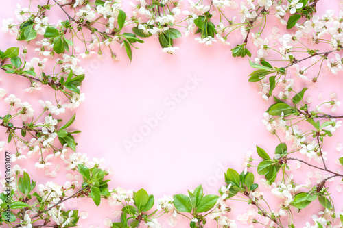Round frame made of blooming cherry branches on pastel pink background. Happy Mother's Day, Birthday or other holiday greeting card. Floral spring background. Flat lay, top view, copy space. © Candle photo