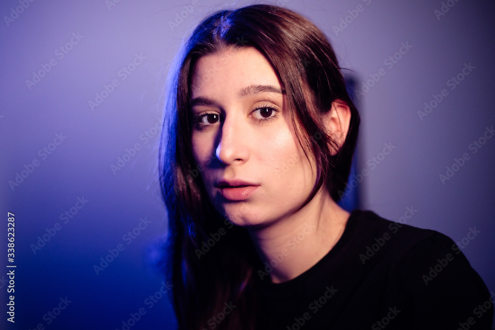 A young beautiful girl is quarantined in an apartment. Low key and blue background A young beautiful girl is quarantined in an apartment. Low key and blue background