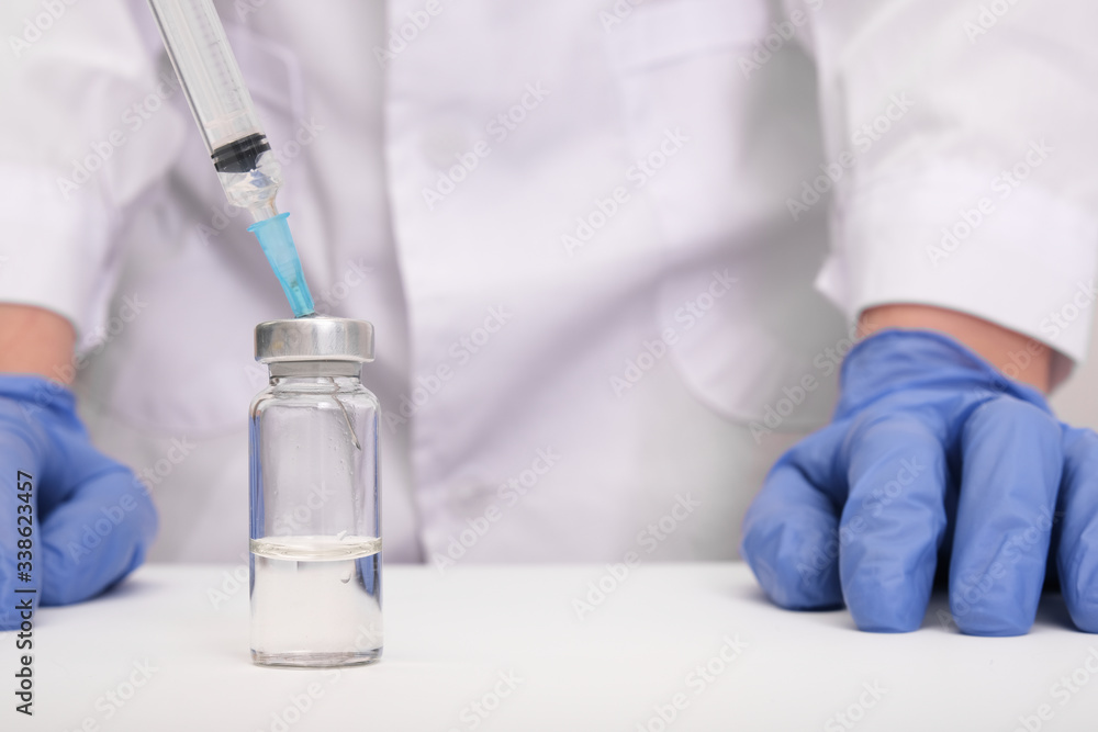 Doctor in blue gloves filling the syringe with vaccine, vaccination and immunization against influenza and coronavirus Doctor in blue gloves filling the syringe with vaccine, vaccination and immunization against influenza and coronavirus