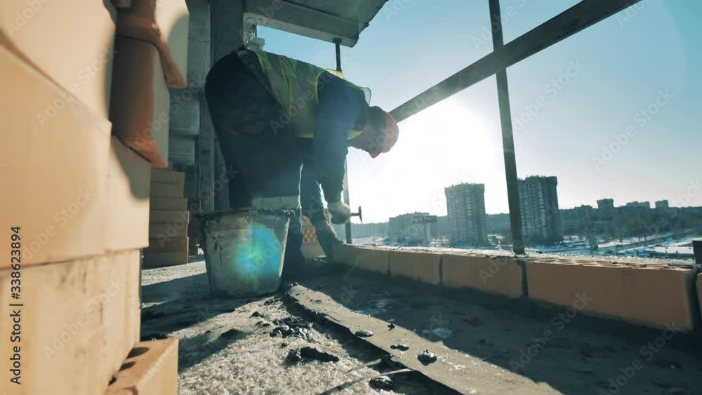 Construction worker is laying bricks on fresh concrete. Construction worker at a construction site.