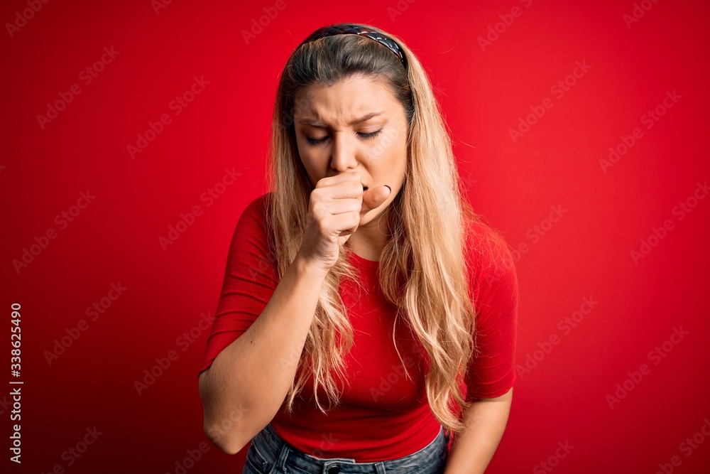 Young beautiful blonde woman wearing casual t-shirt standing over isolated red background feeling unwell and coughing as symptom for cold or bronchitis. Health care concept. Young beautiful blonde woman wearing casual t-shirt standing over isolated red background feeling unwell and coughing as symptom for cold or bronchitis. Health care concept.