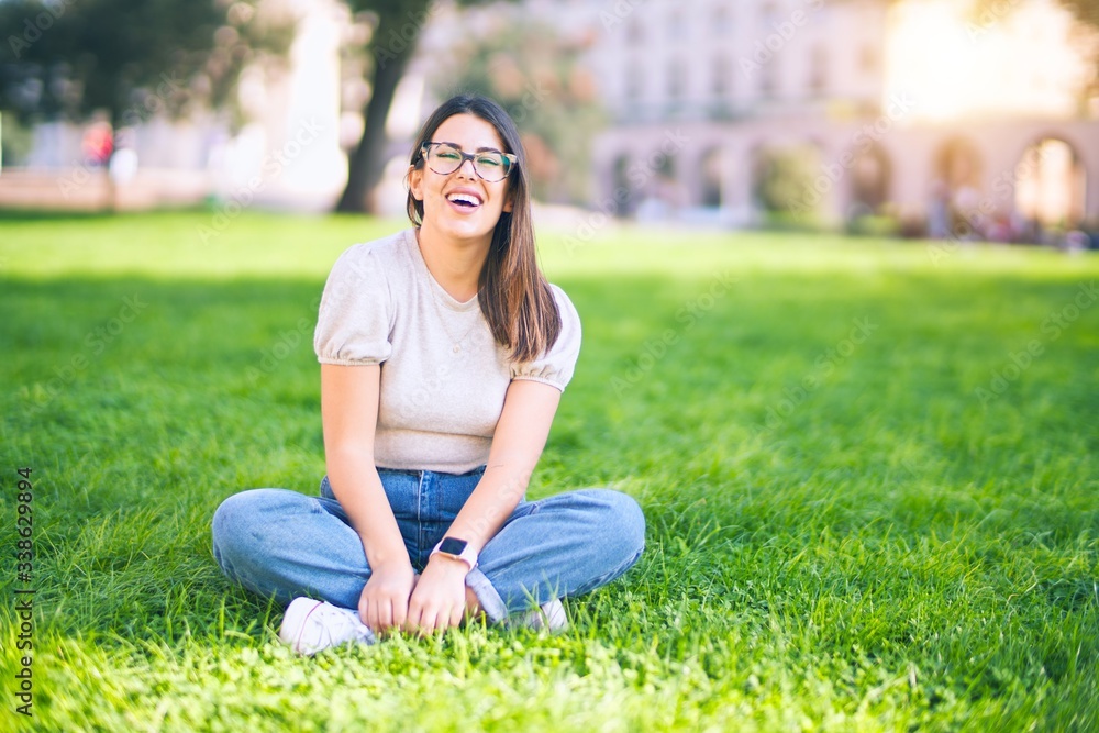 Young beautiful woman smiling happy and confident. Sitting on the grass with smile on face at park Young beautiful woman smiling happy and confident. Sitting on the grass with smile on face at park