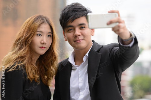 Young Asian business couple taking selfie together in the city