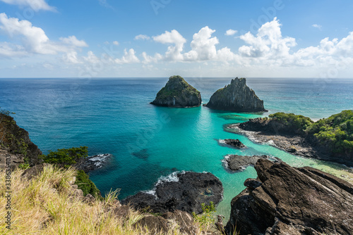 Aerial view of Dois Irmaos Hill at Baia dos Porcos beach, with turquoise clear water, at Fernando de Noronha Marine National Park, a Unesco World Heritage site, Pernambuco, Brazil © MontenegroStock