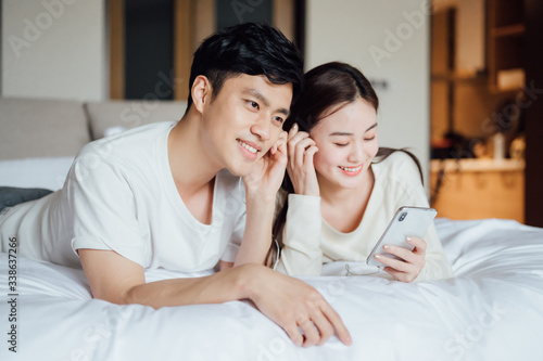 Young Asian couple at home listening to music together