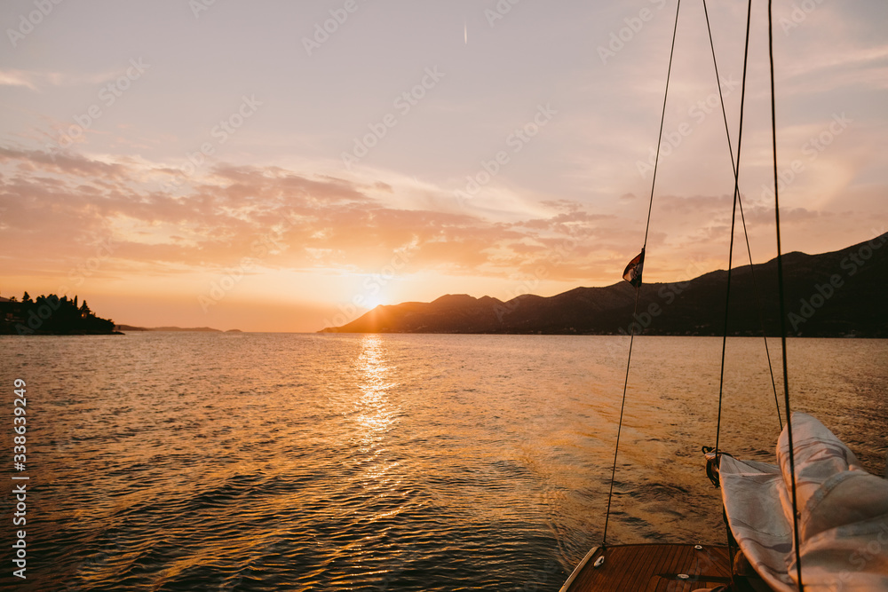 yacht sailing at sunset in sea with mountains view yacht sailing at sunset in sea with mountains view