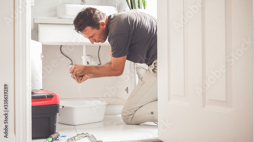 Man At Home Mopping Up Water From Leaking Pipe in Bathroom