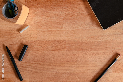 Flat Lay image of a wooden desk with writing tools and an empty space in the middle for copy