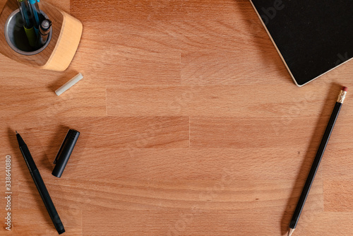 Flat Lay image of a wooden desk with writing tools and an empty space in the middle for copy