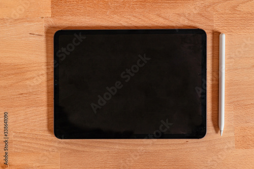 Flat Lay of tablet pro and stylus on a wooden desk with an empty space for copy or vectors