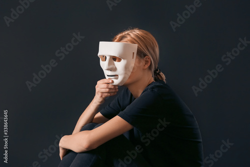 Woman holding mask on dark ...