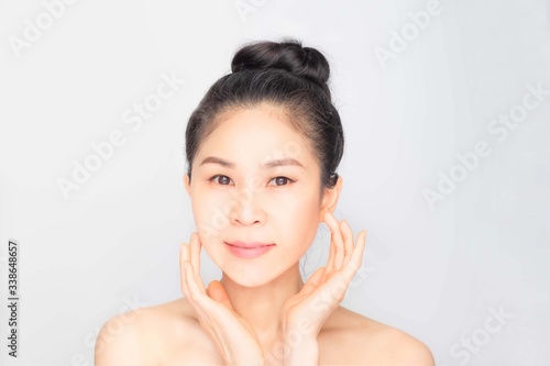 young beautiful asian woman with clean and bright skin  Cosmetic Beauty Concept hands touch on the cheek  smiling and friendly face isolated on grey background
