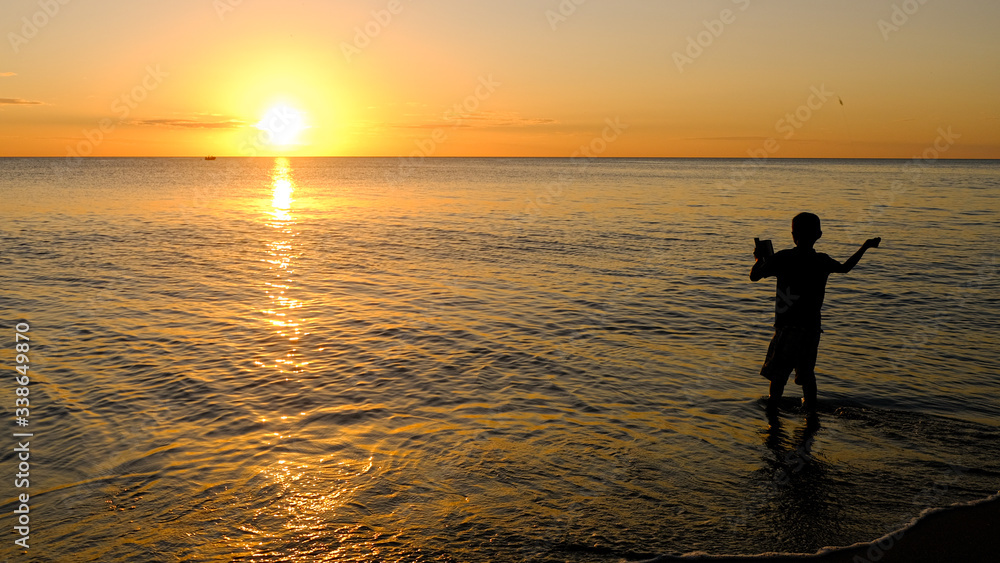 silhouette of a kid fishing in the sunset