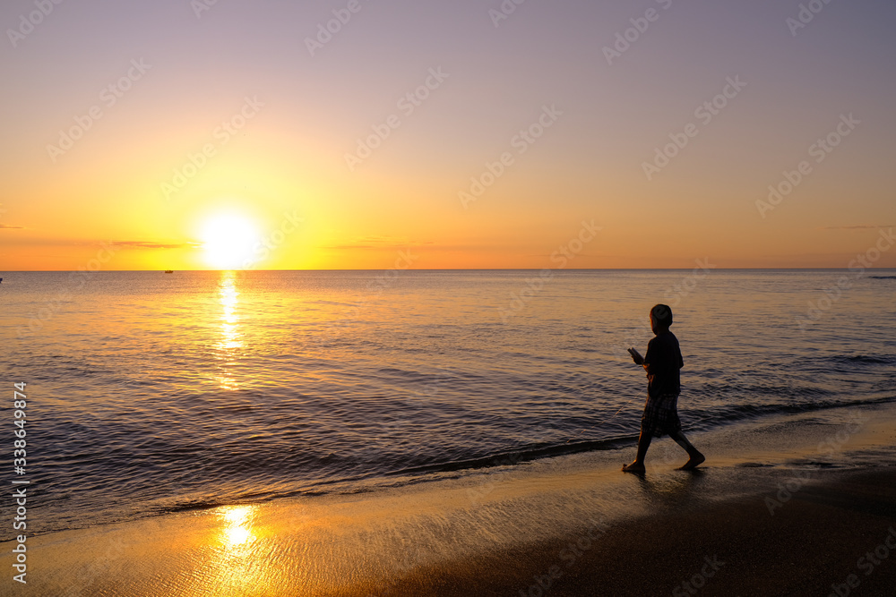 silhouette of a fisher kid  on the beach at sunset