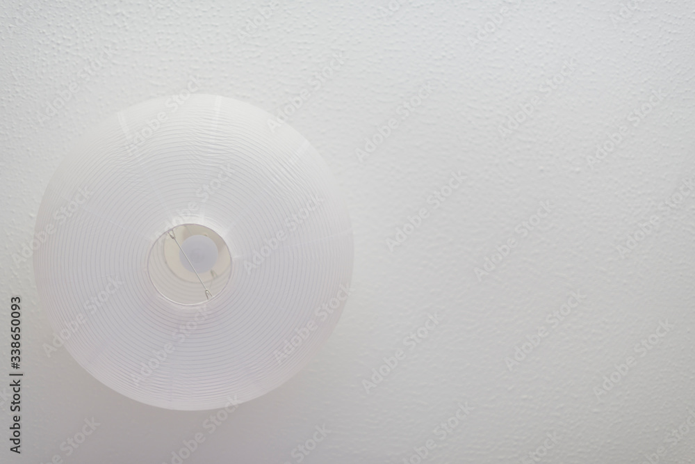 White round ceiling lamp on a white ceiling. White on white White round ceiling lamp on a white ceiling. White on white