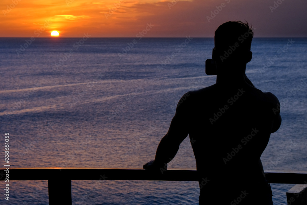 Silhouette of a man taking a picture of the ocean