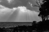 A black and white shot of Beach silhouette with interesting sun rays and cloudscape