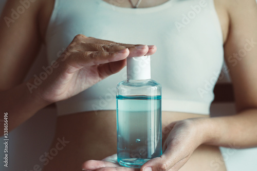 Woman hand holding sanitizer gel bottle for hands hygiene coronavirus protection at home