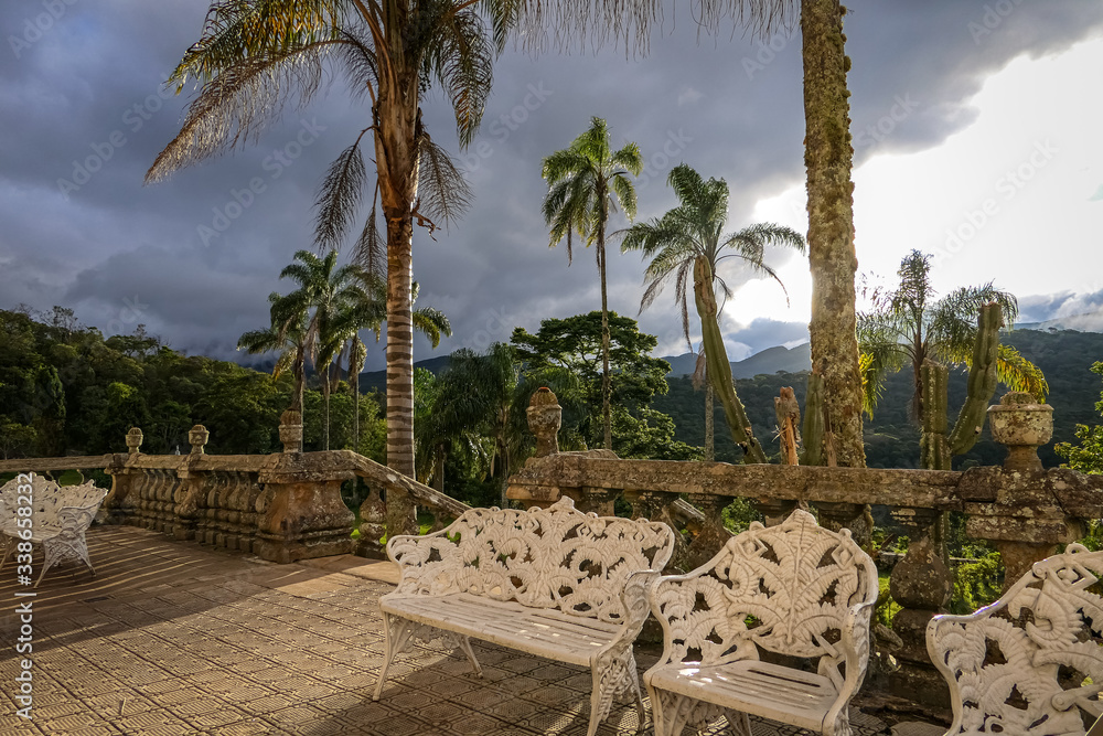 Fototapeta premium View to a terrace in warm light with palm trees and a big grey cloud in the background, Caraca Natural Park, Minas Gerais, Brazil