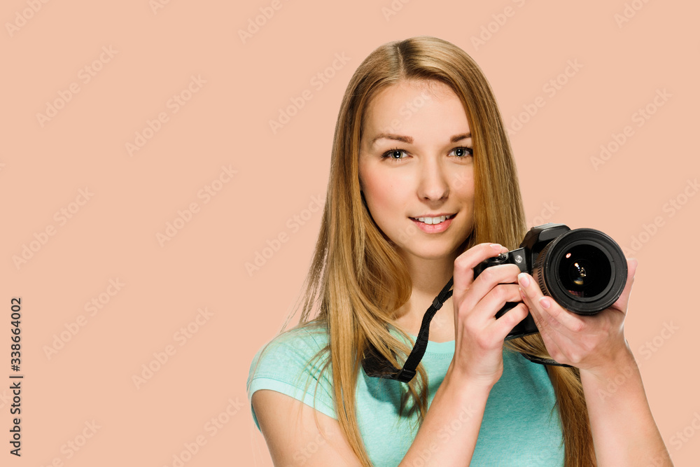Young woman photographer taking photos with dslr camera on salmon shade red background Young woman photographer taking photos with dslr camera on salmon shade red background
