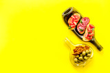 Antipasto on wine bottles on yellow wooden table top-down copy space