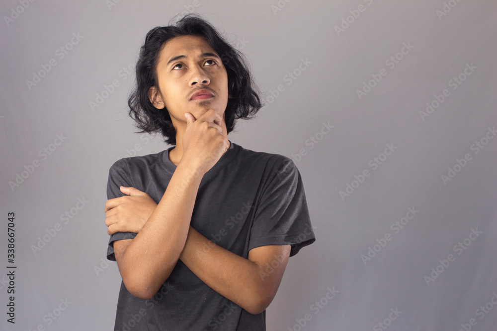 Young man with gery shirt having doubts and with confuse face expression while scratching head on isolated grey background Young man with gery shirt having doubts and with confuse face expression while scratching head on isolated grey background