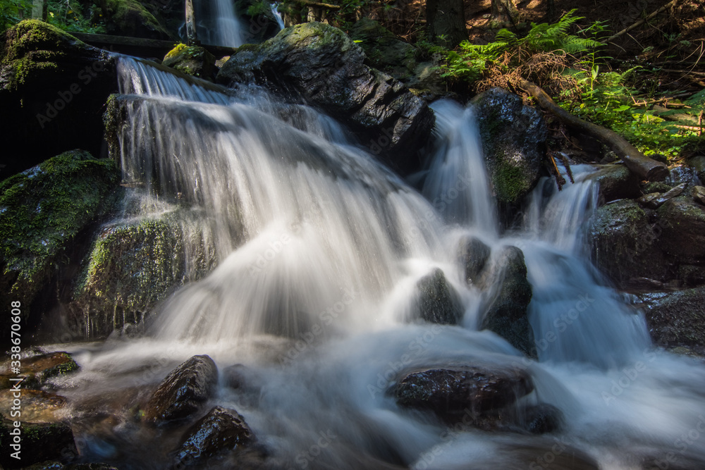 weicher wasserfall mit felsen im wald beim wandern