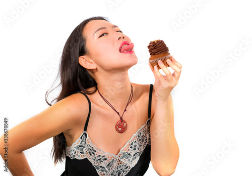 young attractive and happy Asian Chinese woman holding delicious and tempting chocolate cupcake full of calories having dilemma feeling temptation to jump her diet