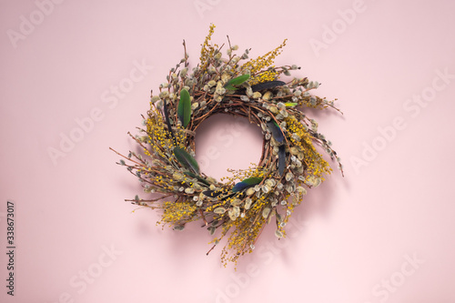 A wreath of dried twigs and flowers on a gently pink background. Natural decoration. Holiday concept. Easter wreath. Willow round frame. Postcard design concept. Copy space.