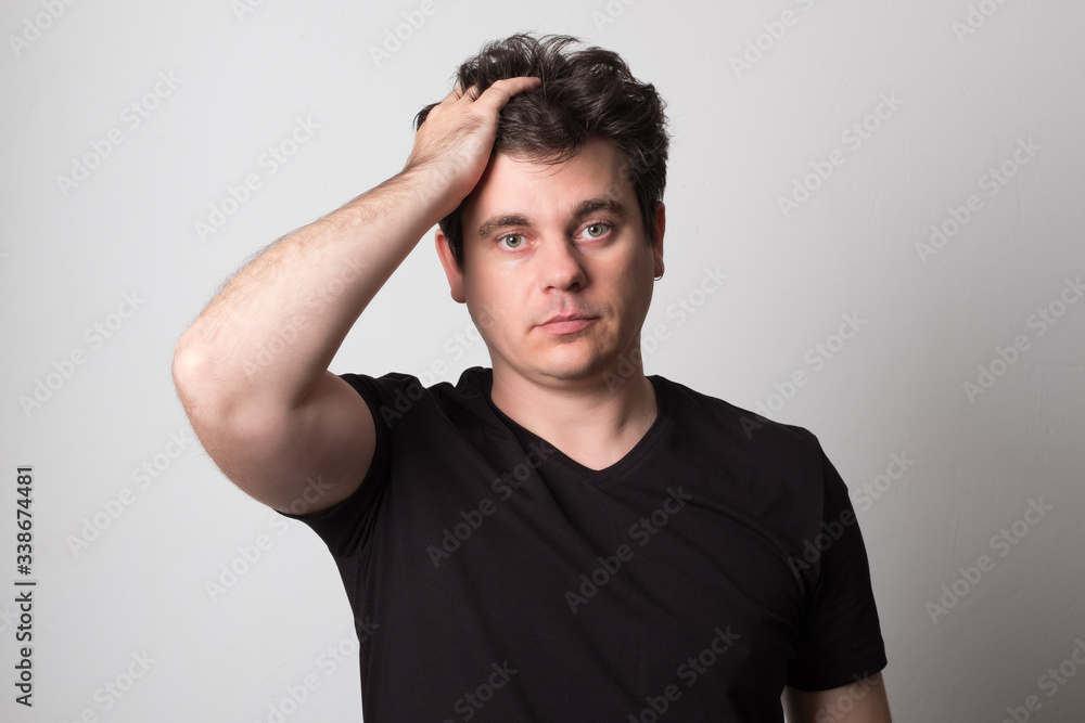 Sad man in a black t-shirt. Young man with beautiful hair. Studio image. Sad man in a black t-shirt. Young man with beautiful hair. Studio image.